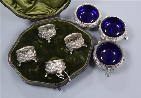 A set of three Victorian embossed silver cauldron salts with blue glass liners and a set of four cased silver salts